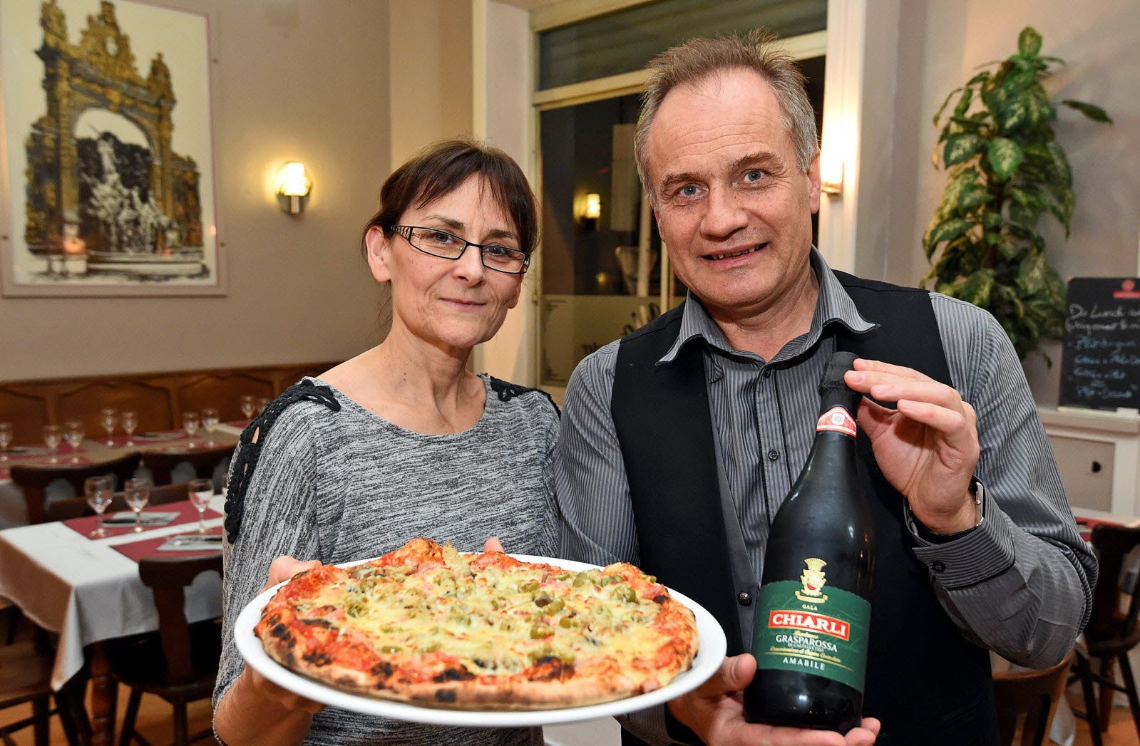 Vesna et Ivan, propriétaires de la pizzeria Sole Mio à Nancy, avec une pizza et une bouteille de vin italien